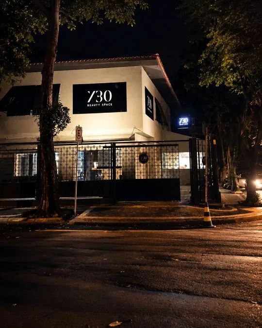 Fachada branca do 730 Beauty Space à noite, com a placa preta